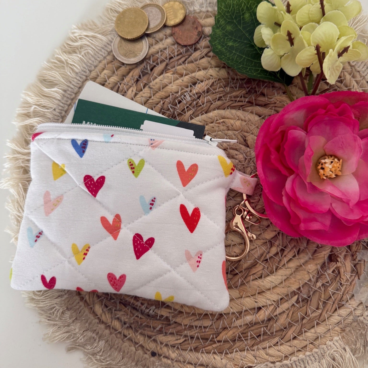 Gequilte witte mini portemonnee met kleurrijke hartjes en metalen clip, gevuld met pasjes en muntgeld