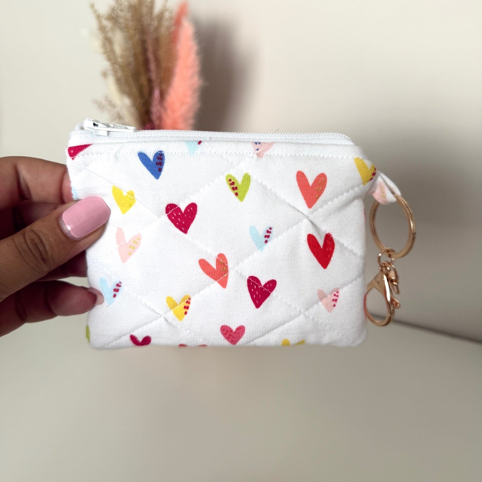 Gequilte witte mini portemonnee met kleurrijke hartjes en metalen clip, gevuld met pasjes en muntgeld